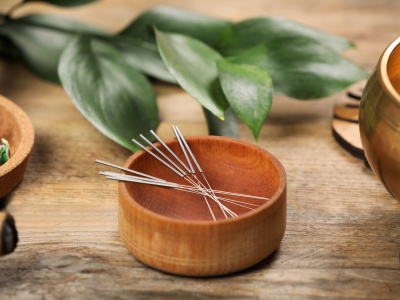 Bowl with acupuncture needles on wooden table